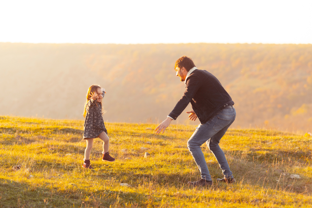 Depositphotos_433230540_S - Renuevo De Plenitud Father and daughter playfully run toward each other in a sunlit grassy field at sunset, sharing a joyful moment.