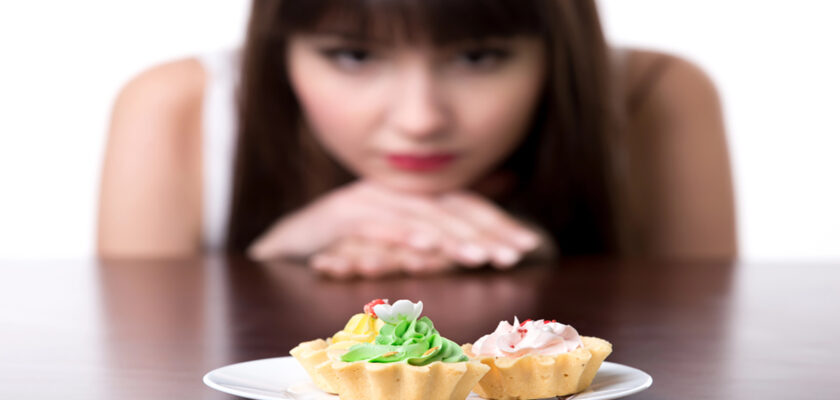 Two decorated mini tarts on a white plate with a blurred woman watching from the background.